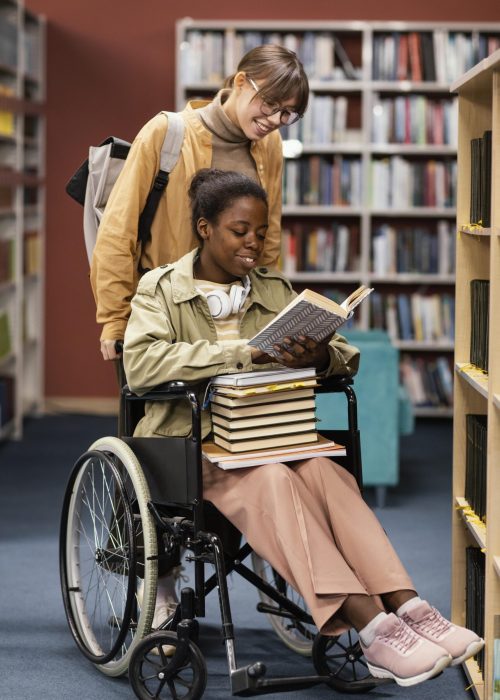 girl-helping-her-colleague-wheelchair-choose-book-project